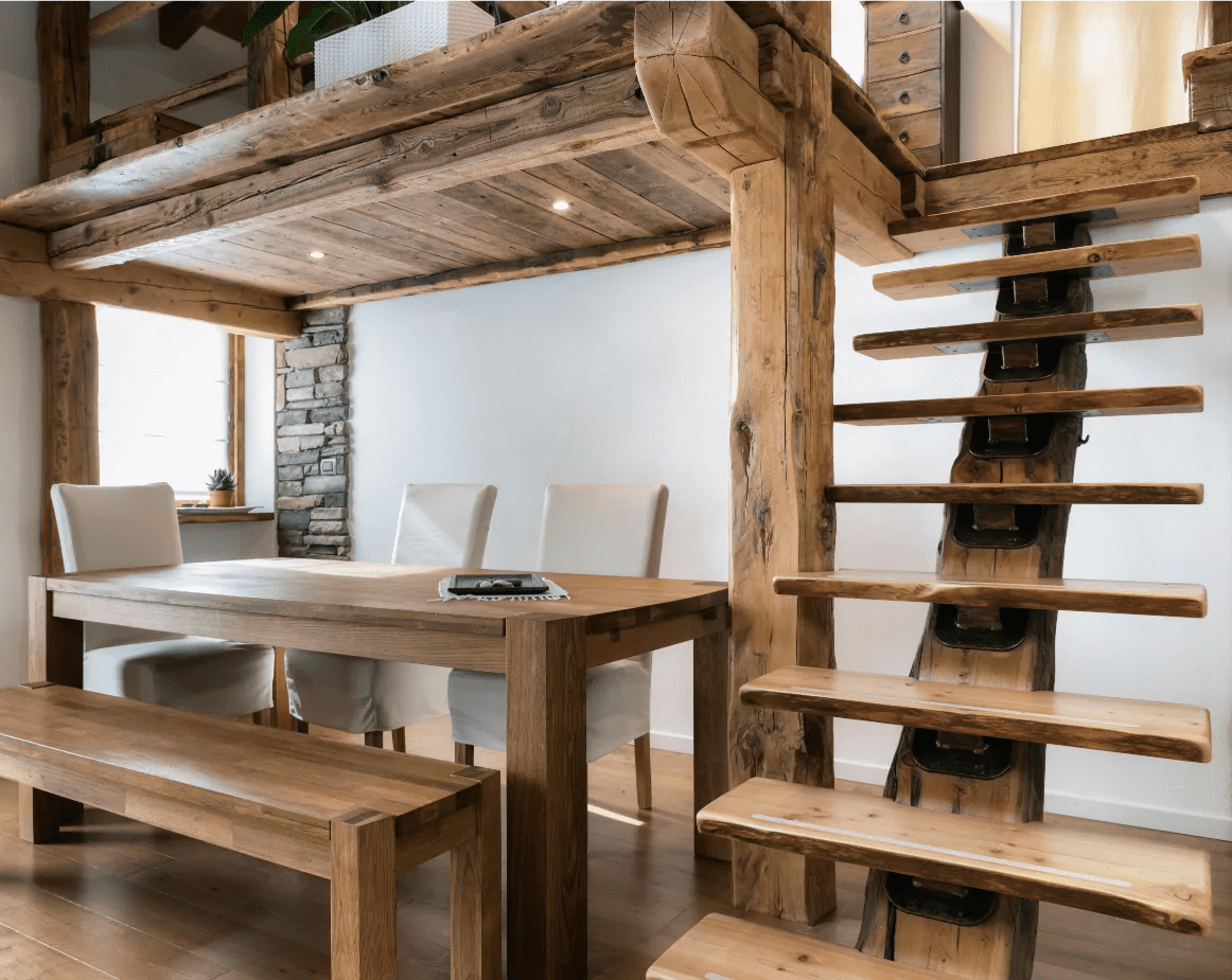 intérieur de maison en bois avec une table, un escalier et une mezzanine